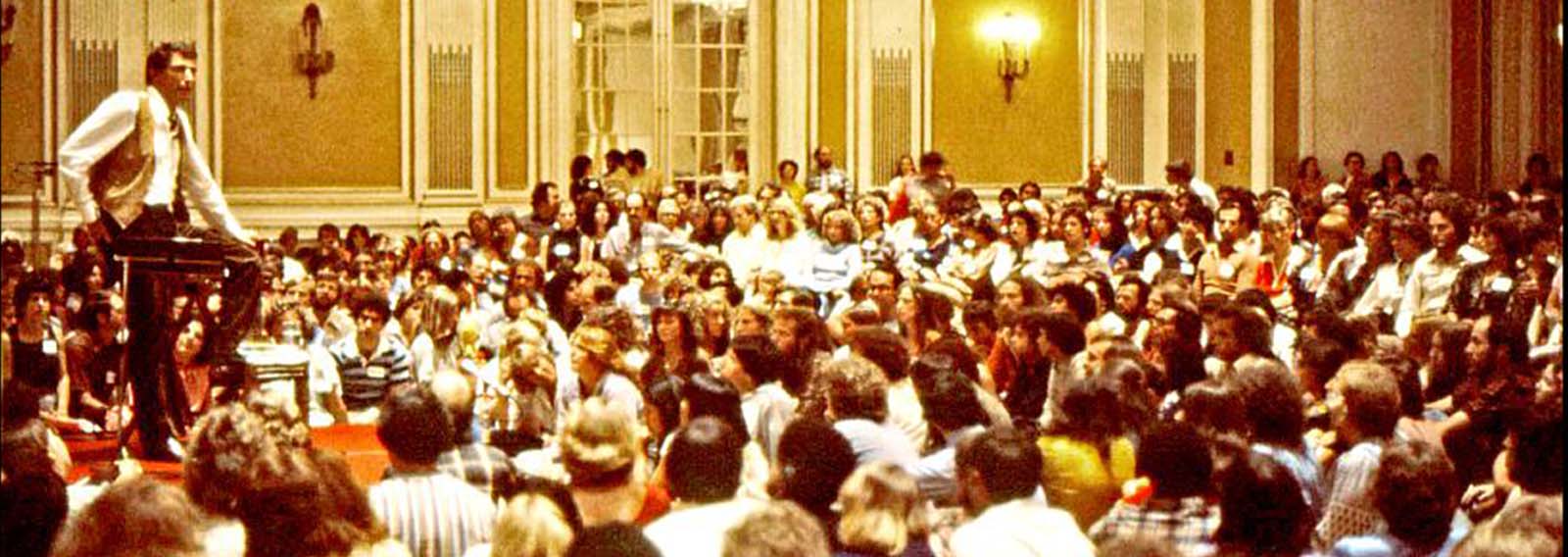 Werner Erhard num de seus seminários: A proposta do treinamento era transformar a forma como se vive, de modo que as situações que a pessoa tentava mudar ou apenas suportava se resolvessem naturalmente, no próprio fluxo da vida.